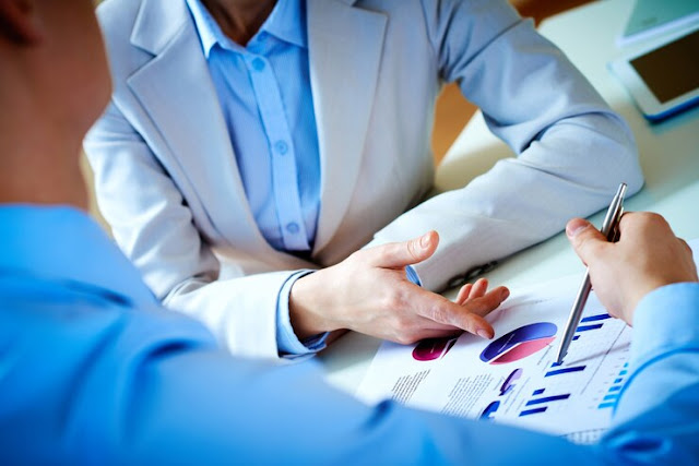 Two professionals analyzing business charts and graphs on paper.